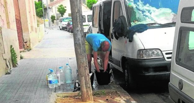 Un trabajador agrícola se lava junto a una furgoneta aparcada en la que pernocta./A. Gómez