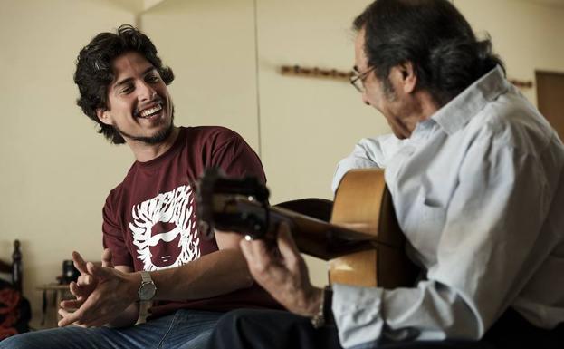 Un músico toca guitarra con su hijo.