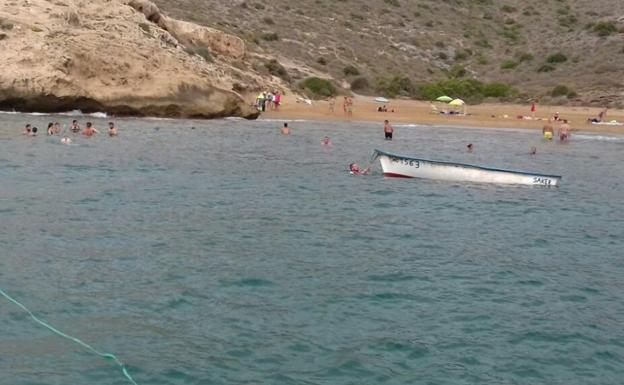 La patera junto a la playa donde desembarcaron los inmigrantes en la mañana del viernes.