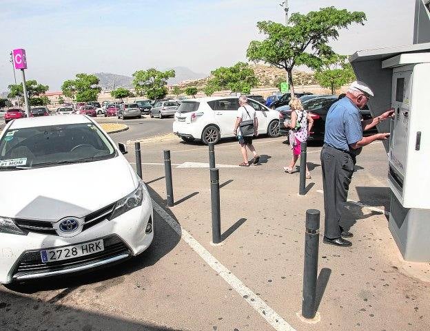 Un hombre paga en el parquímetro, en el parking descubierto del Santa Lucía.