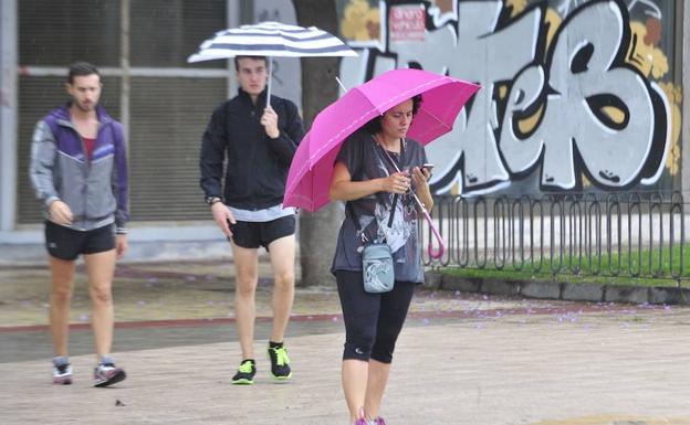 Una mujer se protege de la lluvia en Murcia.