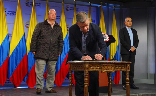 Santos, en el centro, firmando el decreto./