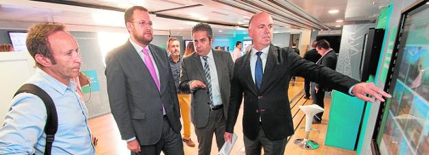 El concejal José Guillén (2º i.) recibe explicaciones de Ramón Albors (d) en el bus de Siemens. /J. C. Caval/ AGM