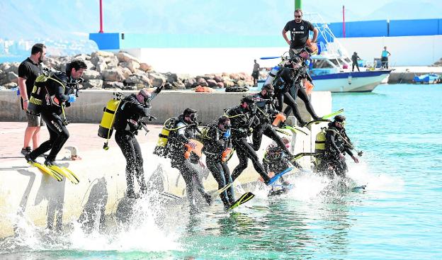 Un grupo de buzos salta a las aguas del Puerto Pesquero de Mazarrón, el pasado sábado, en busca de residuos marinos./Alfonso Durán / AGM