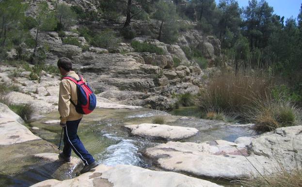 Un senderista cruza el cauce del río Alhárabe, a medio camino entre el embalse de La Risca y La Puerta./M. A. R.