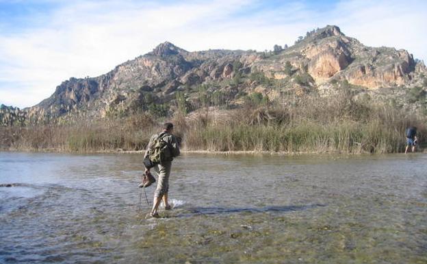 Un senderista cruza el río junto a la finca de El Hondón./
