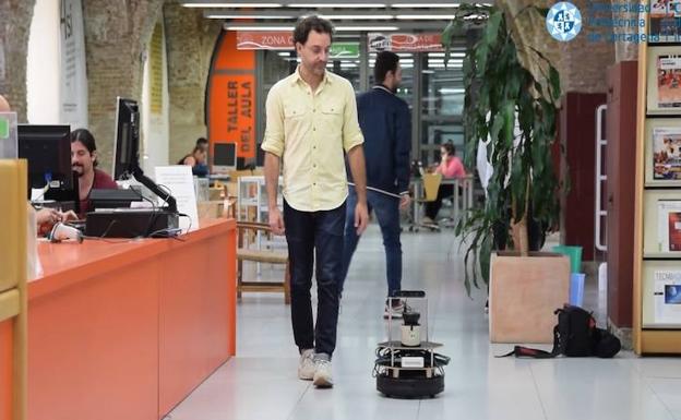 El robot acompaña a un usuario de la biblioteca. /UPCT