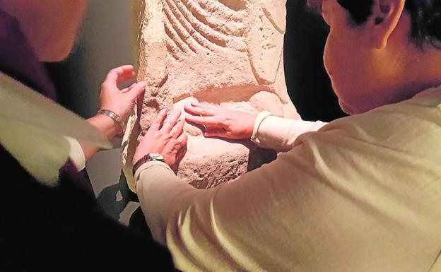 Dos visitantes reconocen el relieve de una obra con sus manos. / CARM