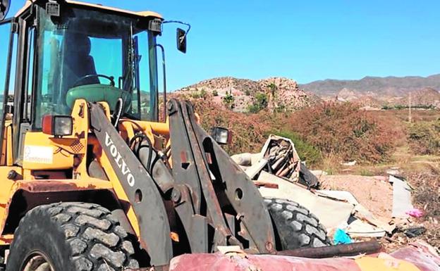 Un tractor retira un sofá abandonado en un vertedero ilegal./Ayto