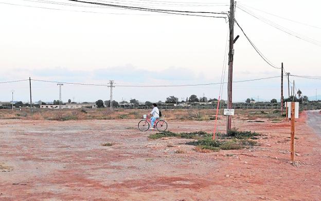 Una ciclista pasa por los terrenos donde se construirá el nuevo colegio de La Aljorra./Pablo Sánchez / AGM