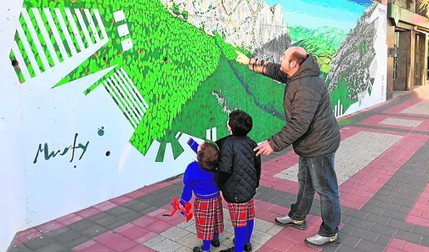 Un hombre muestra el mural del Valle de Leiva a dos niños./P. E.