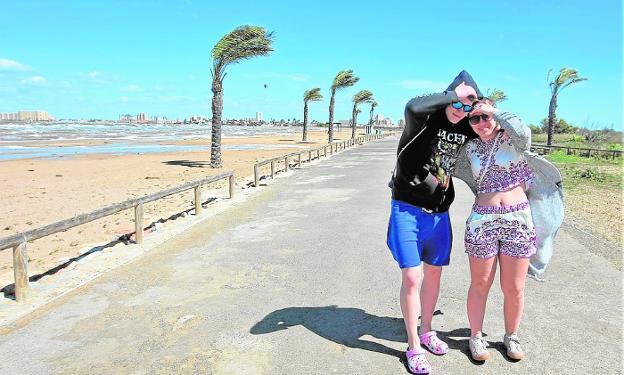 Una pareja se protege la cara del viento, ayer, en La Manga. / p. m.