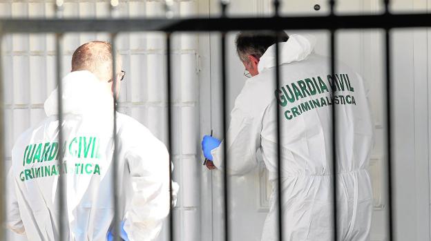 Especialistas en Criminalística de la Guardia Civil analizando, en la mañana de ayer, la puerta de la casa donde se produjo el crimen./Edu Botella