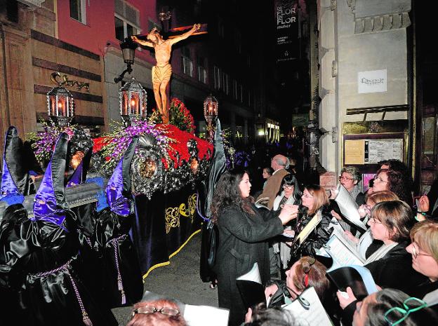 El trono del Santísimo Cristo del Refugio, sobre un calvario de rosas rojas, a su paso por la calle Trapería./VICENTE VICÉNS / AGM