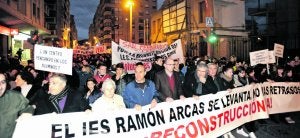 La cabeza de la manifestación, anoche, a su paso por los restos que quedan en pie del insituto Ramón Arcas Meca tras ser demolido por los daños del terremoto. :: P. ALONSO / AGM/