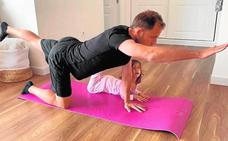 El capitán del Cartagena, Miguel Ángel Cordero, hace estiramientos en el salón de su casa, bajo la atenta mirada de su hija./FC CARTAGENA