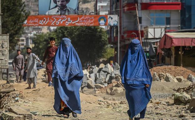 Dos mujeres caminan por la calle, ante la mirada de los hombres, en Kabul/AFP