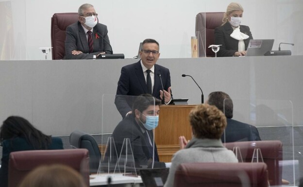 Diego Conesa intervenes in the session while López Miras speaks with his deputies. 