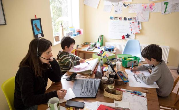 A woman works from home to care for her children in a file image. 