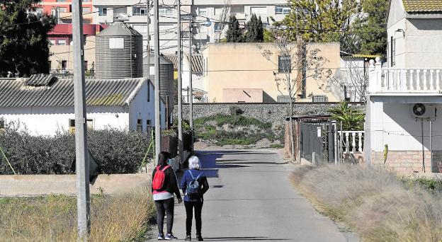 Two neighbors walk along the Camino del Encallao, which separates a house from a couple of pig feedlots. 
