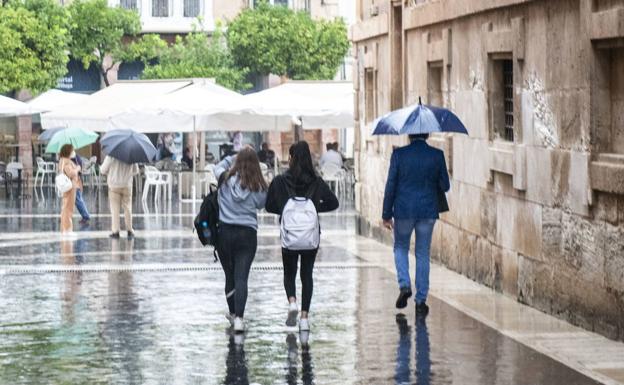 Two girls walk without umbrellas on a rainy day.