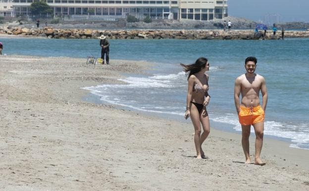 Two young people walk along the Sirenas beach, with the Galúa hotel in the background, in La Manga in a file photo. 