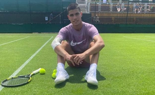 Carlos Alcaraz poses sitting on a Wimbledon court yesterday. 