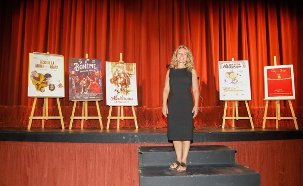 The Councilor for Culture on the stage of the War Theater next to some of the posters of the planned performances. 