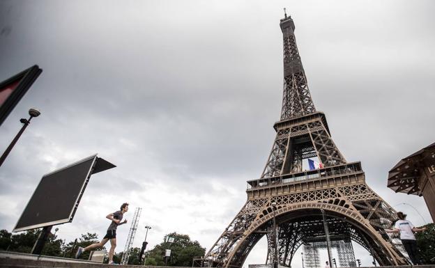 A man runs next to the Eiffel tower