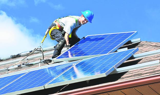 A technician installs solar panels on the roof of a house. 