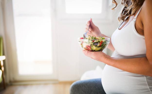 A pregnant woman eating a salad.