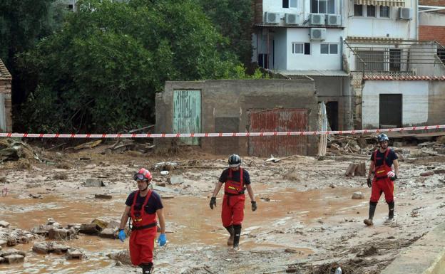 Firefighters walk down a street devastated by the flood in an image from last Monday.