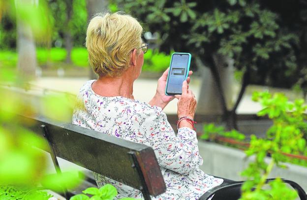 An elderly person surfs the internet with his mobile. 