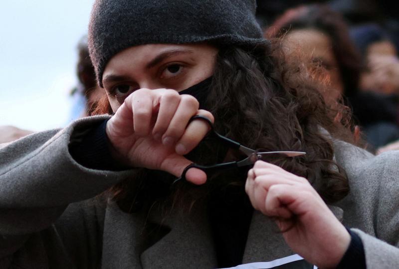 A young Iranian woman cuts off a lock of her hair in defiance of the regime during a demonstration protesting the death of Masha Amini