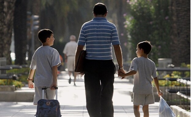 A father accompanies his children to school in Valencia. 