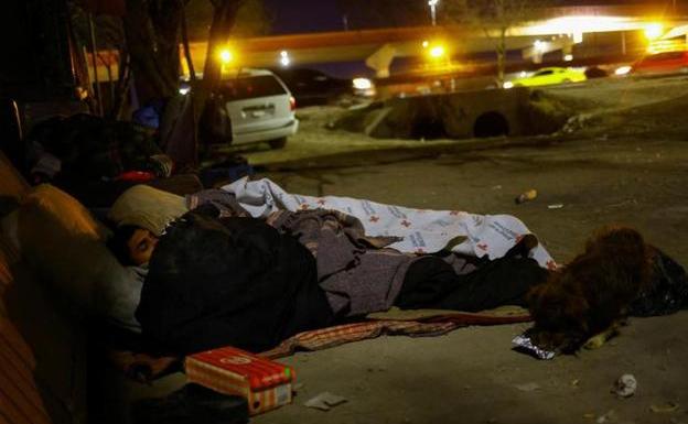A group of migrants sleep on the street near the border, waiting for the opportunity to cross it.