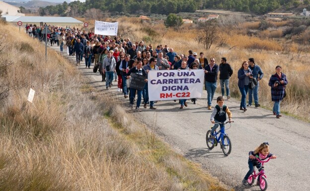 Neighbors with protest banners walk along the RM-C22 highway during the demonstration. 